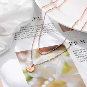 Detail of rose gold layered necklace with letter S pendant on an elegant white tray
