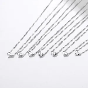 Close-up of seven silver heart pendants with engraved letters A to G on delicate chains