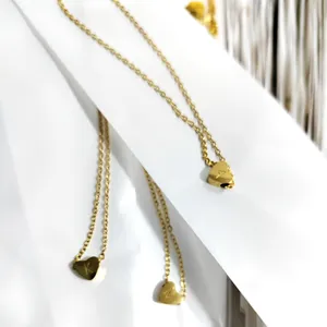 Three gold heart initial necklaces with A, K, M engravings on a white background