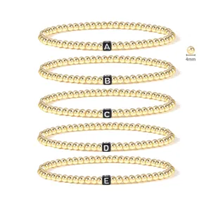 Detail of 4mm 18K gold-plated beaded stretch bracelets with black letter A-E charms
