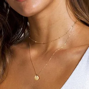Detail of 18K gold double layer necklace with beaded satellite chain and letter M pendant