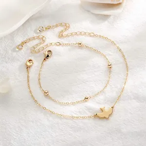 Detailed macro view of two-piece gold anklet set with bird pendant and bead chain elements
