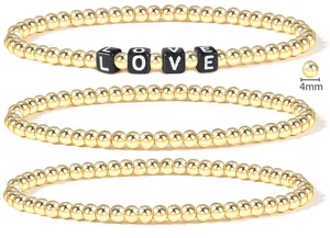 Detail of three 4mm golden beaded bracelets set with LOVE letter beads on white background