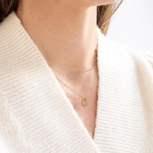 Close-up of double-layered gold necklace with 18K finish and round letter K coin pendant
