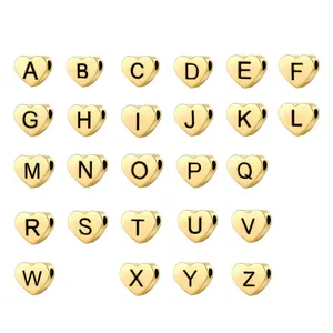 Macro view of gold-plated heart beads with black engraved A-Z letters for DIY jewelry