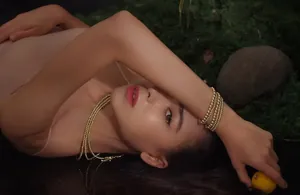 Detail of layered gold beaded bracelet and necklace set on a model with natural moss