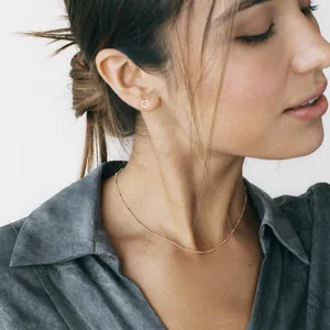 Detail of 18K gold-plated double-layer necklace and round stud earrings on a model