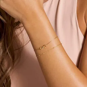 Detail of 18K gold plated double layer chain bracelet with infinity symbol on wrist