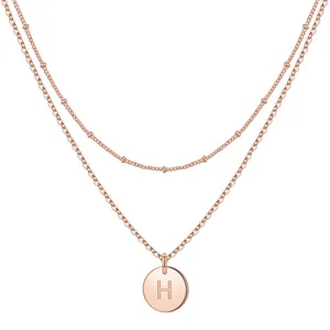 Close-up of double layer necklace in rose gold with initial H coin and beaded satellite chain