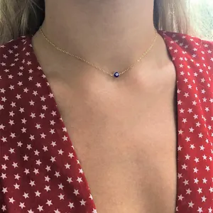 Close-up of a gold-plated evil eye pendant necklace worn by a model on a star-print dress