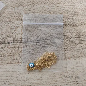 Gold stainless steel evil eye necklace with blue pendant on a light wood background