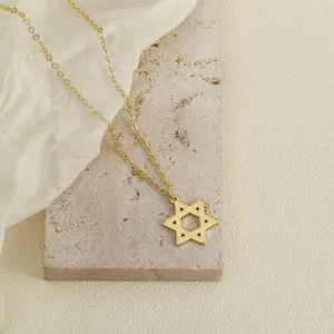 Detail shot of a golden Star of David pendant on a delicate chain over a stone block