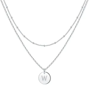 Macro detail of silver double-layered chain necklace with round letter W pendant