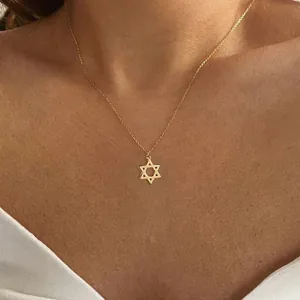 Detail of a dainty gold stainless steel Star of David pendant necklace on a female neck