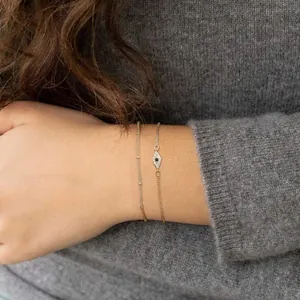 Detail of layered gold evil eye bracelet with freshwater pearl and tiny pavé stones