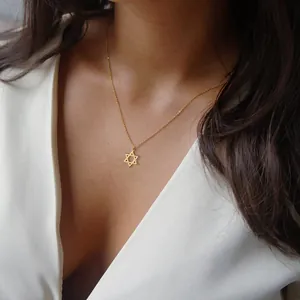 Macro shot of minimalist gold David Star pendant on a delicate stainless steel cross chain
