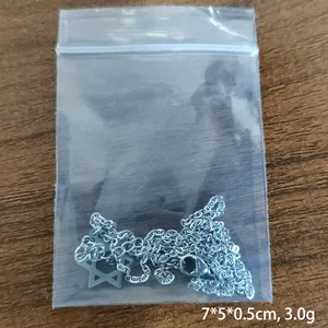 Detailed view of David Star necklace with cross chain in clear packaging on dark wood
