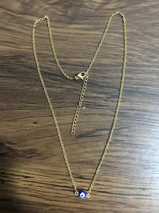 Detailed shot of golden stainless steel chain with evil eye pendant and lobster clasp