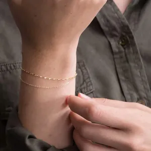 Detail of 18K gold-plated stainless steel layered chain bracelet on a female model wrist