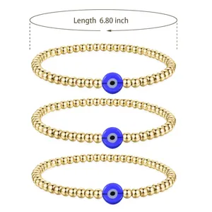 Detailed close-up of three gold beaded bracelets with blue evil eye charms in a set