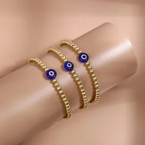 Detailed macro view of three gold beaded bracelets with blue evil eye charms on a display stand