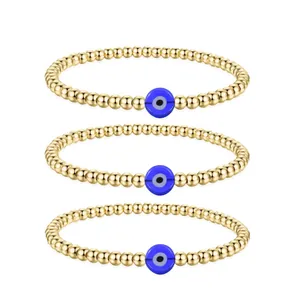 Detailed view of three gold beaded bracelets featuring blue evil eye charms and metal beads