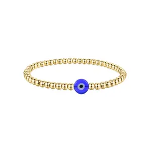Macro detail of golden stainless steel beads and blue Evil Eye charm bracelet