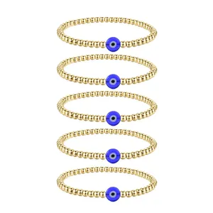 Detailed set of five gold beaded bracelets featuring blue evil eye charms on white background