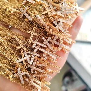 Handheld stack of gold plated stainless steel cross necklaces with sparkling zircon pavé