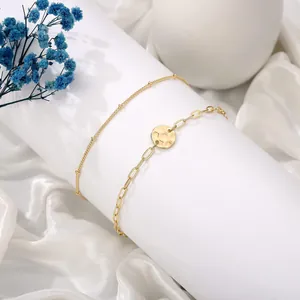Detail of 18K gold-plated double-layer bracelet with textured round coin pendant and paperclip chain