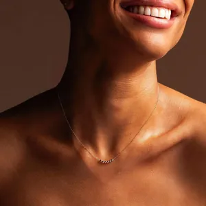 Detailed view of minimalist stainless steel necklace with five sliding 18K gold beads