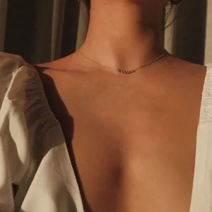 Minimalist gold necklace with sliding beads worn by a model in warm elegant sunlight
