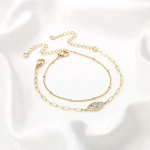 Detail of double-layer gold bracelets with evil eye charm and adjustable lobster clasp