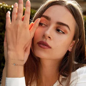 Gold paperclip chain bracelet set with zircon evil eye charm on a female wrist