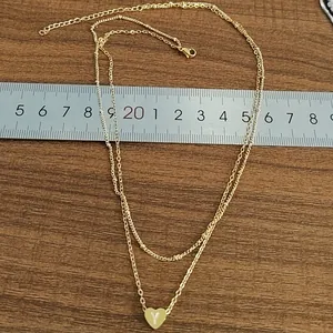 Double layered gold heart necklace featuring engraved letter Y pendant on wooden surface