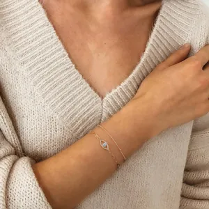 Close-up of a double-layered 18K gold evil eye bracelet set on a knitted sleeve