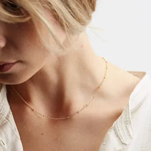 Detail of 18K gold-plated beaded chain necklace elegantly worn on a model's collarbone