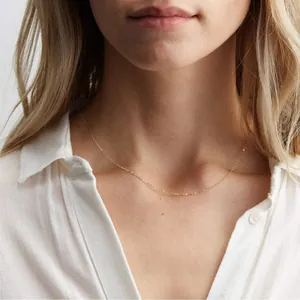 Close-up of minimalist layered 18K gold plated stainless steel disc pendant necklace on model