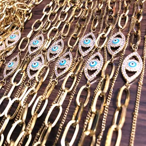 Detail van gouden paperclip kettingarmband met strass boze oog bedeltje op hout