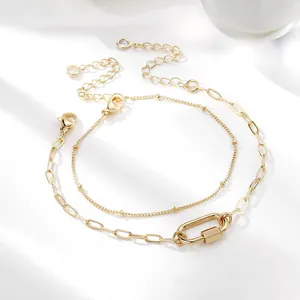 Detail van dubbellaagse gouden paperclip-armband met kralenketting en karabijnsluiting