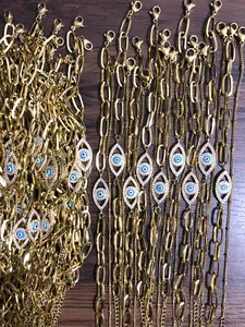 Detail van gouden rechthoekige schakelketting met een schitterende blauwe boze oog hanger