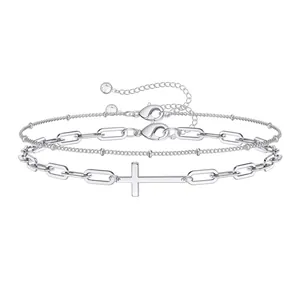 Detail van een zilveren dubbellaagse armband met kruishanger en een stevige karabijnsluiting
