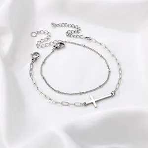 Detail van zilveren roestvrijstalen kruisarmbandset met karabijnsluiting op zijden stof