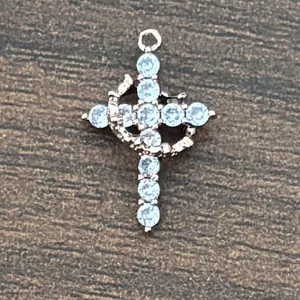 Macro shot of 18K gold plated cross pendant with cubic zirconia on wood background