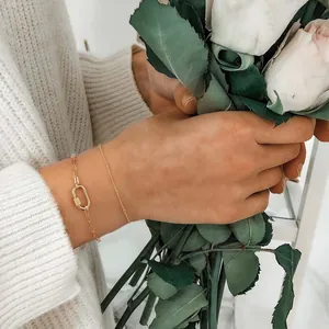 Detail van 18K vergulde dubbellaagse armband met Cubaanse schakel en ovale sluiting om de pols