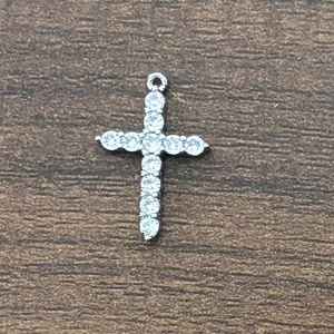 Detailed view of silver cross pendant with micro-pave zircons on a wooden background