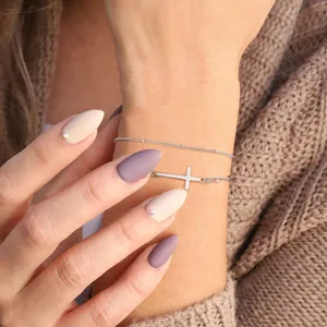 Macro-opname van een zilveren horizontale kruisarmband met fijne kralenketting