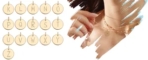 Detail of round gold initial pendants and layered paperclip chain necklace