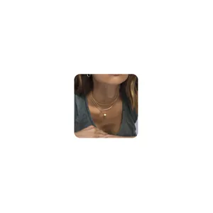 Detail of layered gold necklace with tube pendant and coin disc on a model's neck
