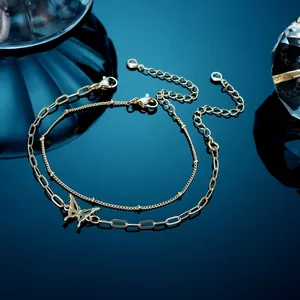 Macro-detail van gouden dubbellaagse armband met een holle vlinderbedel van roestvrij staal